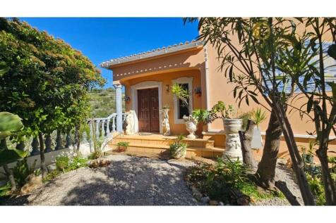 Main entrance of a villa with terracotta-toned façade and garden