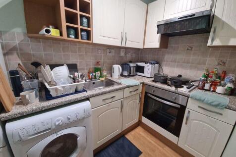 A compact kitchen area with white cabinetry, a ...
