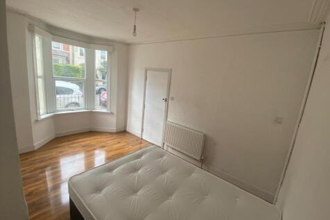 Bright bedroom with large bay window and wood f...