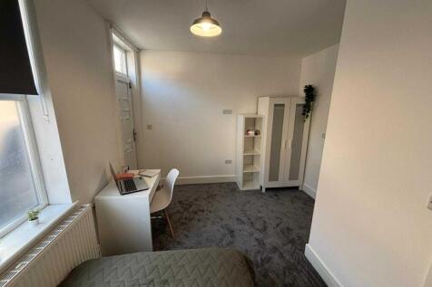 A bright and clean bedroom featuring a small de...