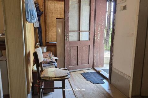 A room with a wooden chair, table, and an open door leading to the outside area.
