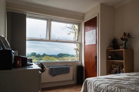 A cozy single bedroom featuring a large window ...