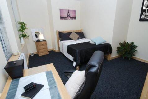 Bright master bedroom with large desk and bed...