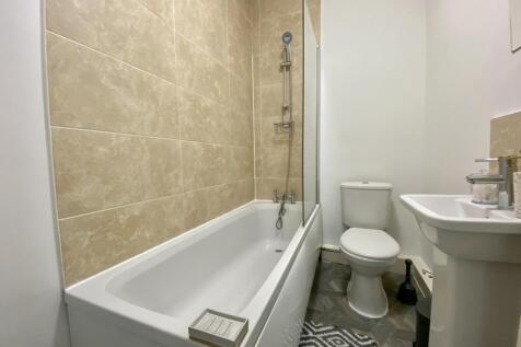 A clean and modern bathroom featuring a bath an...