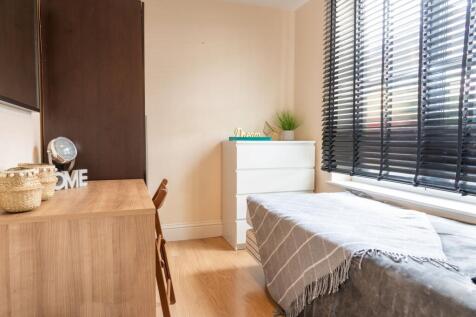 Bright, tidy bedroom with a neatly made single ...