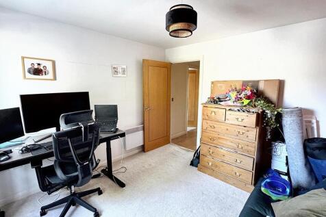 A spacious, well-lit living room featuring a de...