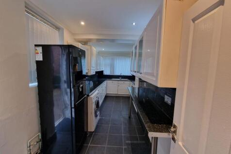 Modern galley kitchen with glossy black worktop...