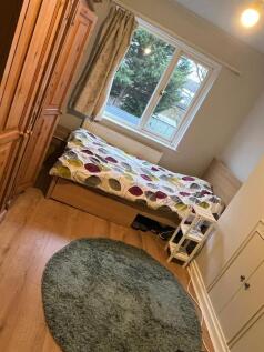 Bright bedroom with large window and wood floor...