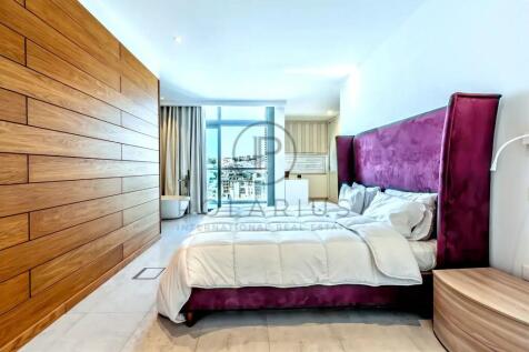 A modern bedroom featuring a bed with a plush purp