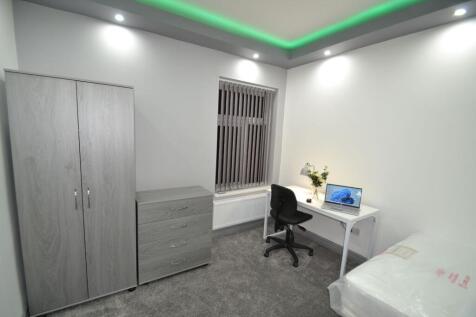 A bright and tidy student room featuring a stud...