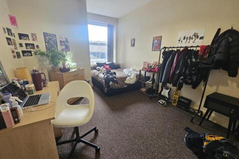 Compact furnished bedroom with a desk, comforta...