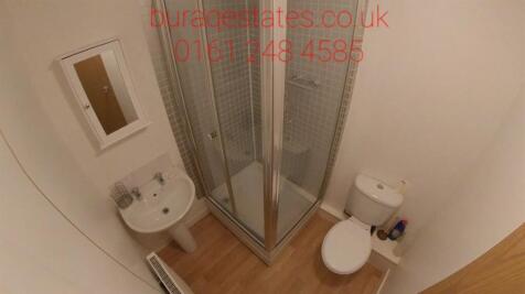 Clean compact bathroom with a corner shower cub...
