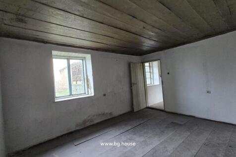 Interior view of an empty room featuring a wooden ceiling, white walls, wooden floor, and a window.