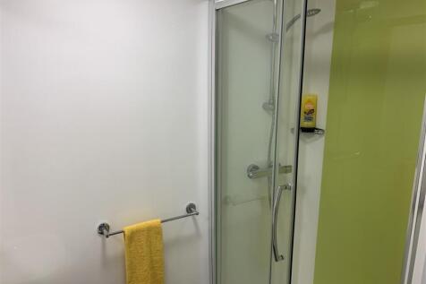 Bright bathroom with glass shower and towel rai...