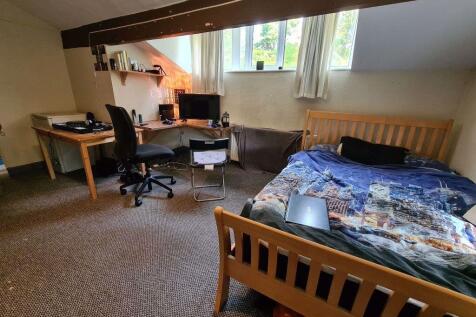 A cozy double bedroom featuring a wooden bed wi...