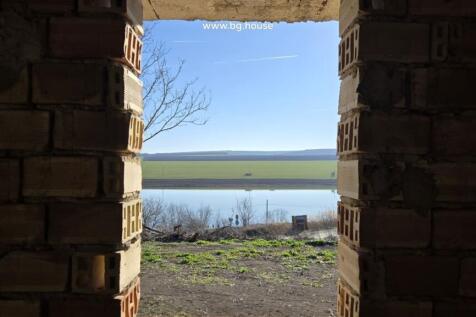 View of lake and open fields seen through an unfinished brick wall opening in the villa.