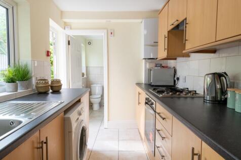 Bright modern galley kitchen with light wood ca...