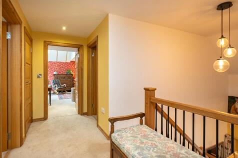 A beautifully lit landing with oak bannisters, ele