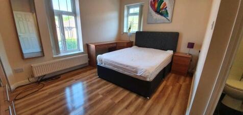 Bright double bedroom with desk and wood floori...