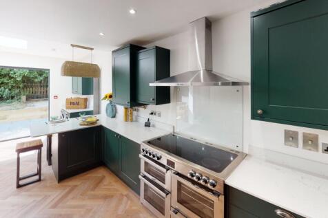 Modern kitchen with sleek dark green cabinetry,...