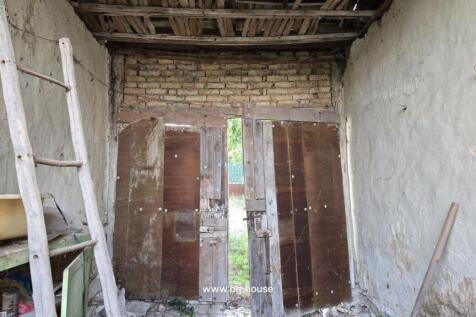 Covered outdoor space showing wooden doors and old furniture, similar to adjacent image.