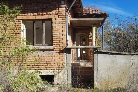 The front entrance of the brick house featuring concrete steps leading to a small porch area with a doorway and window.