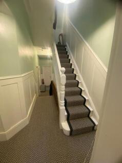 Bright, neatly kept hallway with a carpeted sta...