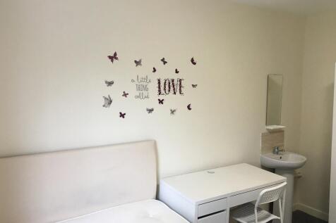 A simple, tidy single bedroom featuring a white...