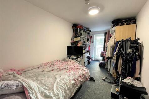 Bright, long bedroom with a comfy bed, built sh...