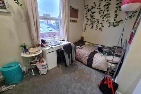 Cozy single bedroom featuring a neatly made bed...