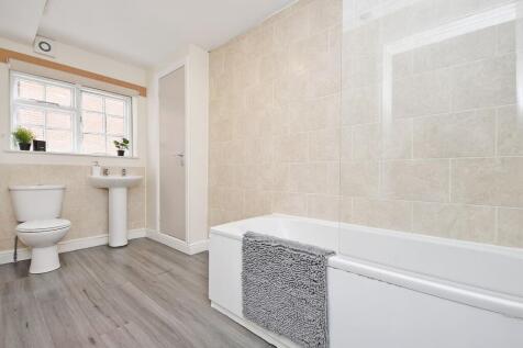Bright, modern bathroom with tiled walls, a ful...