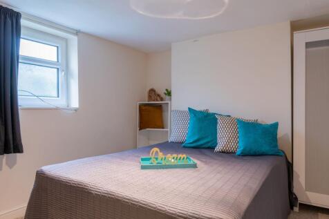 Bright, neatly styled bedroom with a comfortabl...