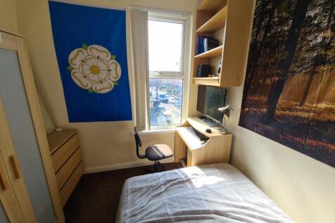 A cozy student bedroom bathed in natural light ...