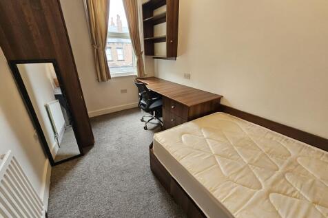 A neat, well-lit single bedroom featuring a des...