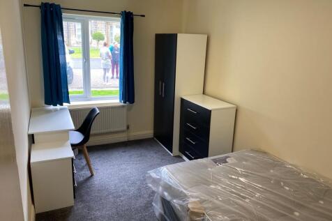 A well-lit, tidy single bedroom with a window p...