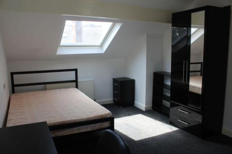 A well-lit bedroom with a sloped ceiling, skyli...