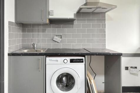 Compact modern kitchenette with grey cabinetry,...
