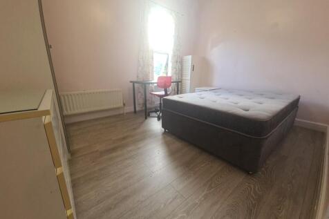 A spacious double bedroom with a comfortable be...