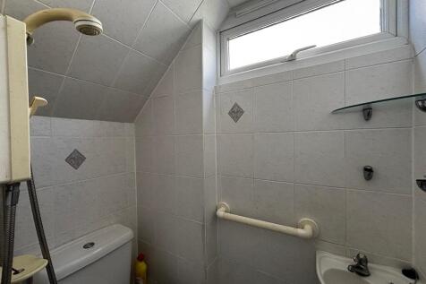 Bright fully tiled bathroom with shower and win...