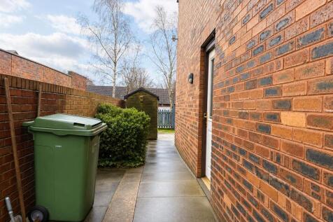 Neat paved side entrance leading to a quiet gar...