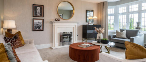 Living room with cream sofas, a fireplace, large bay windows, and modern decor in a bright, stylish