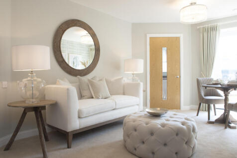 a living room with a white couch and a round mirror