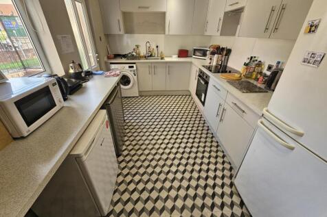 Bright, modern galley kitchen with white cabine...