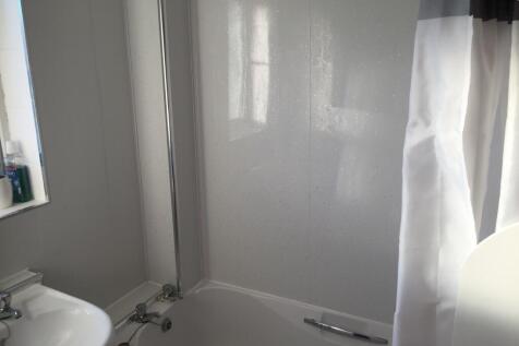 Bright, modern bathroom with a white bathtub, s...