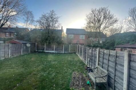 Private rear garden with a well-kept lawn, bord...