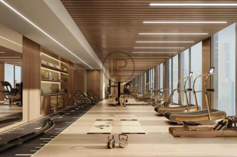 A modern gym with large windows, featuring treadmi