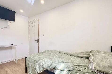 Bright bedroom with wall-mounted TV and desk....