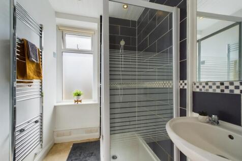 A modern, clean bathroom featuring a glass-encl...