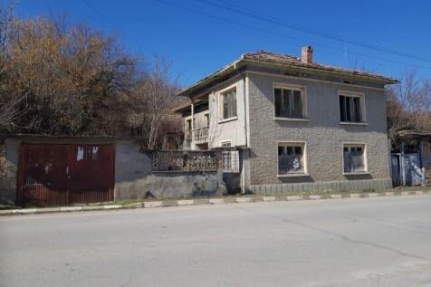 Front view of a two-storey house with a tiled roof and textured walls in Nikolaevo village