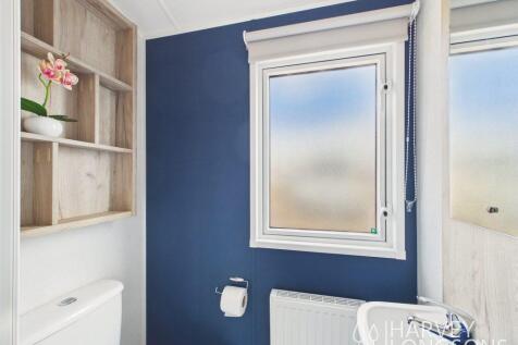 En-suite toilet with sink, storage and blue featur